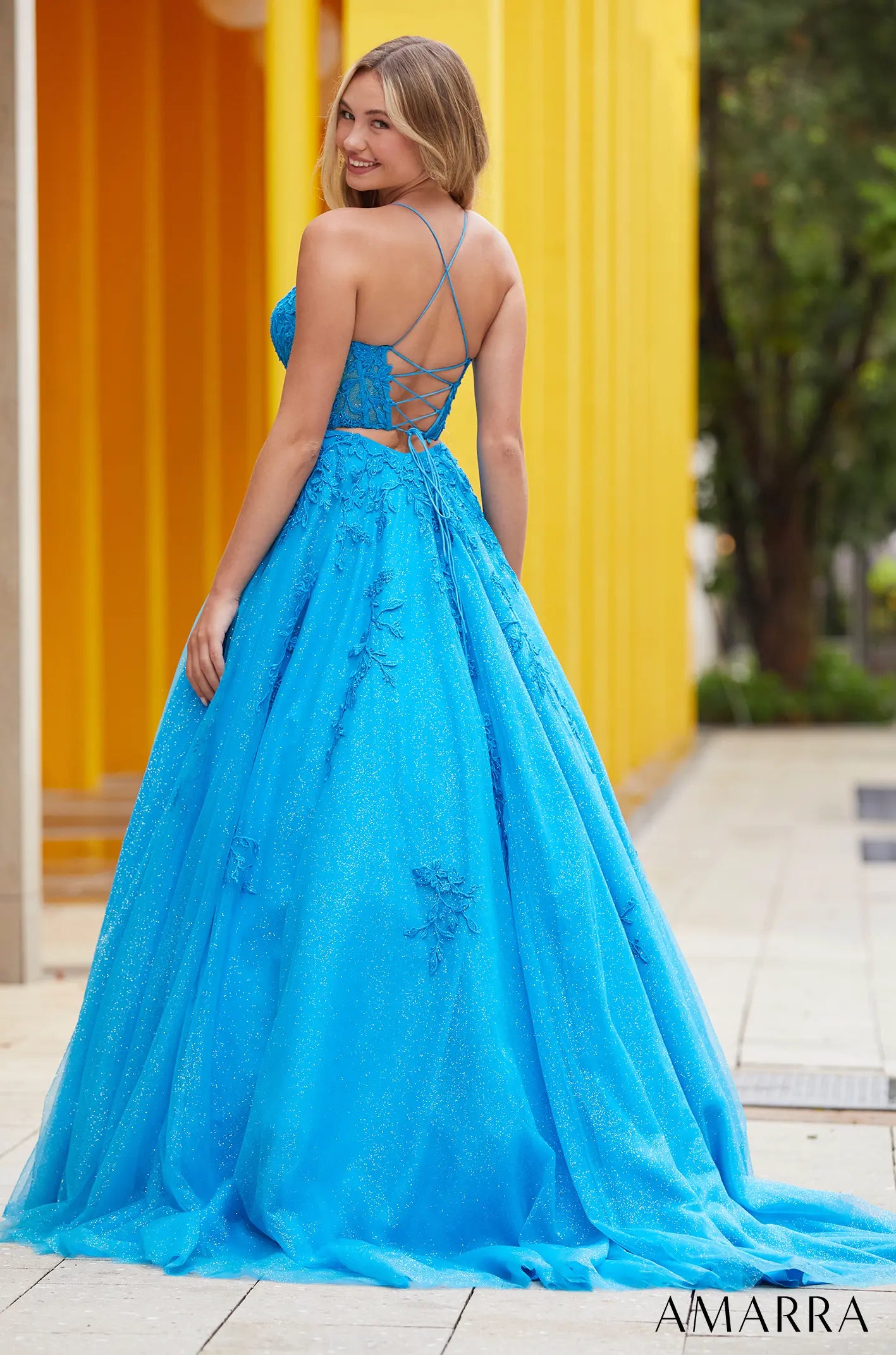Woman in a blue evening gown with a yellow building in the background