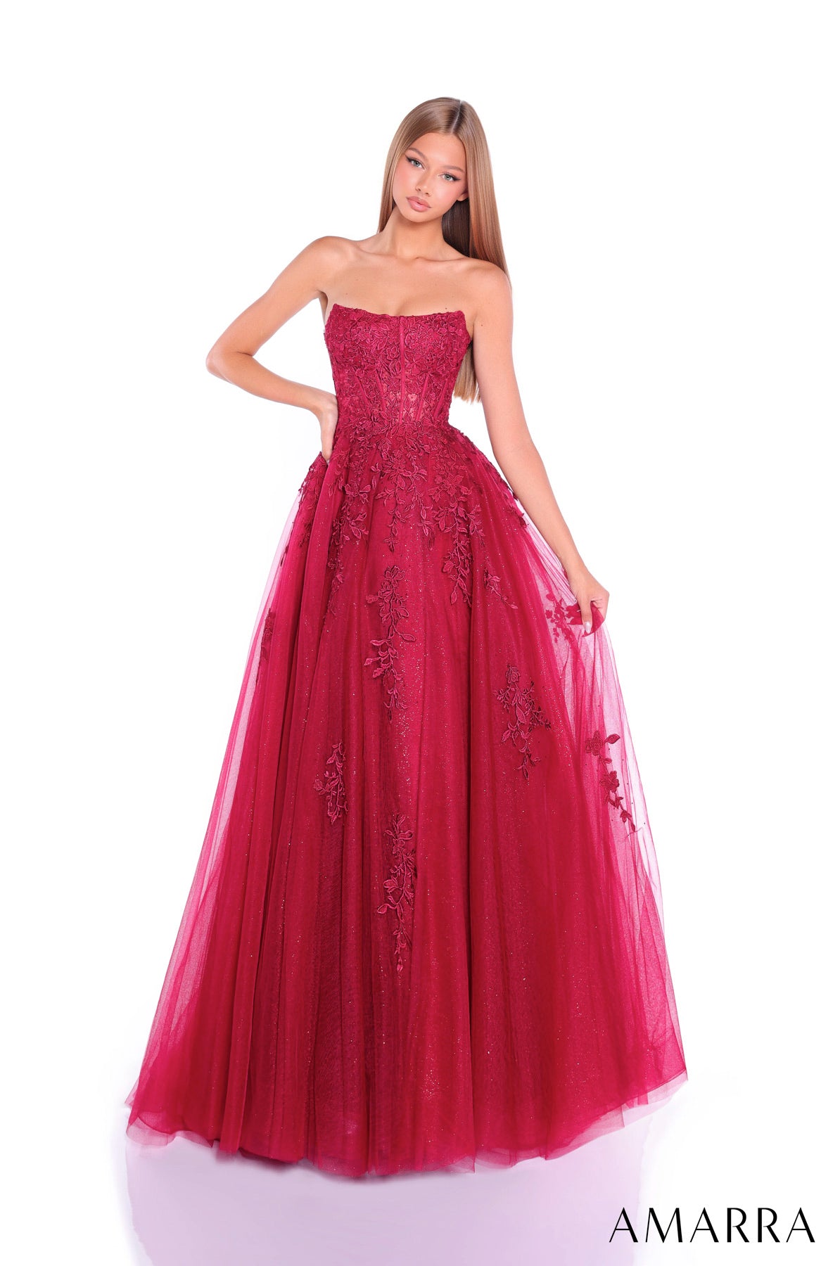 Red strapless gown with floral embroidery on a white background, brand 'AMARRA' visible. THE BRIDAL COMPANY