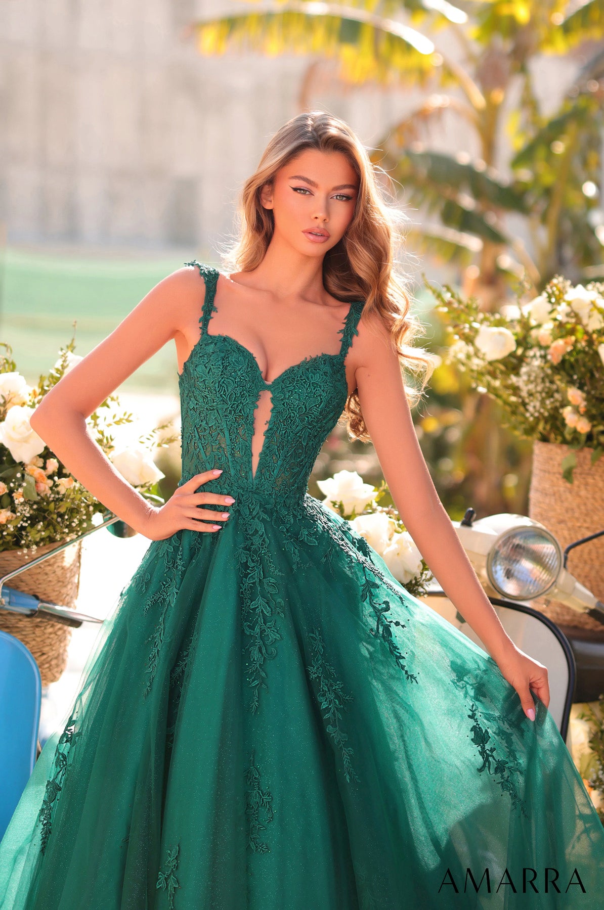 Woman in a green evening gown with floral decorations in the background THE BRIDAL COMPANY
