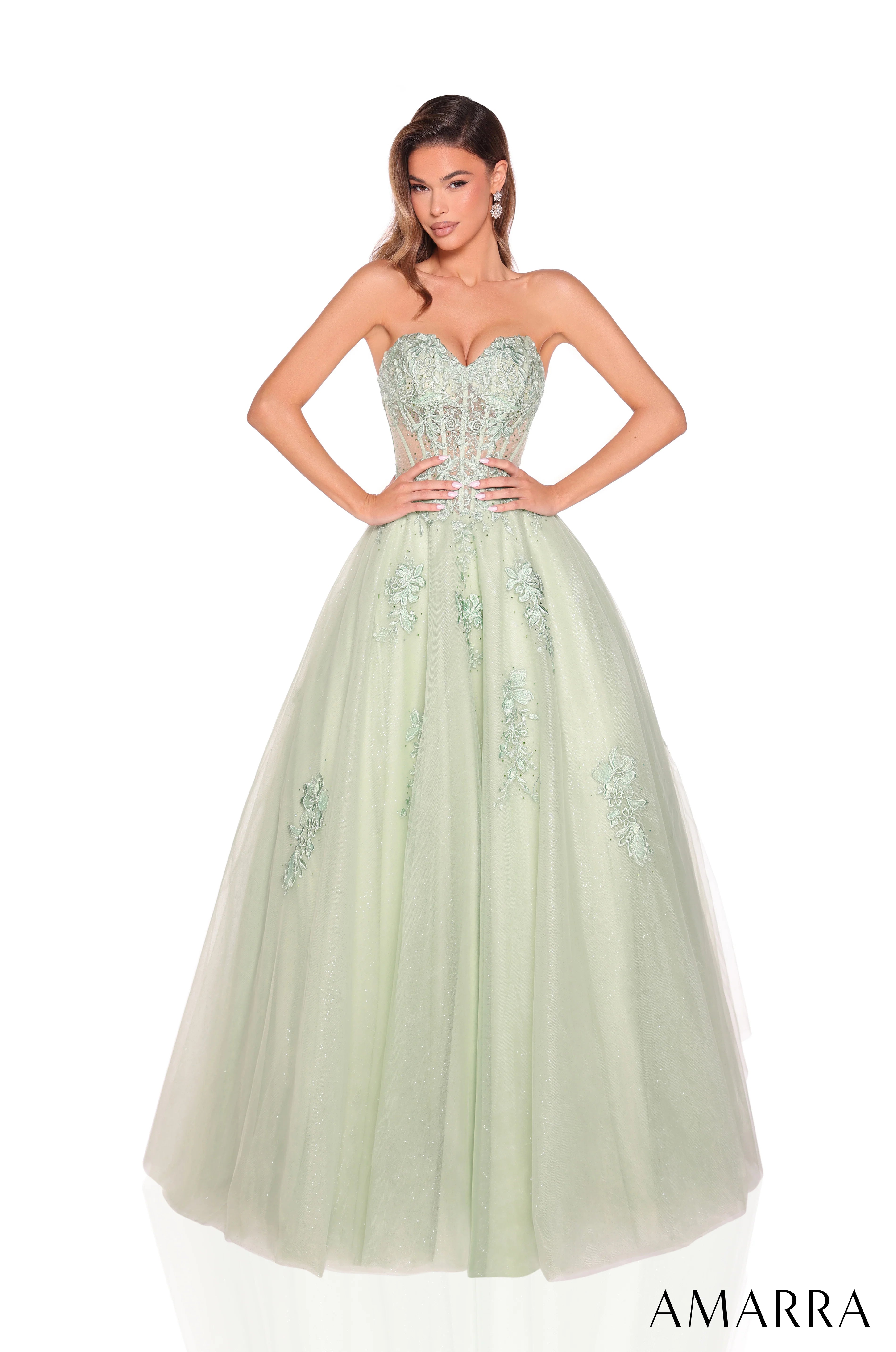 Woman wearing a light green strapless gown with floral embellishments on a white background, brand 'AMARRA' visible.