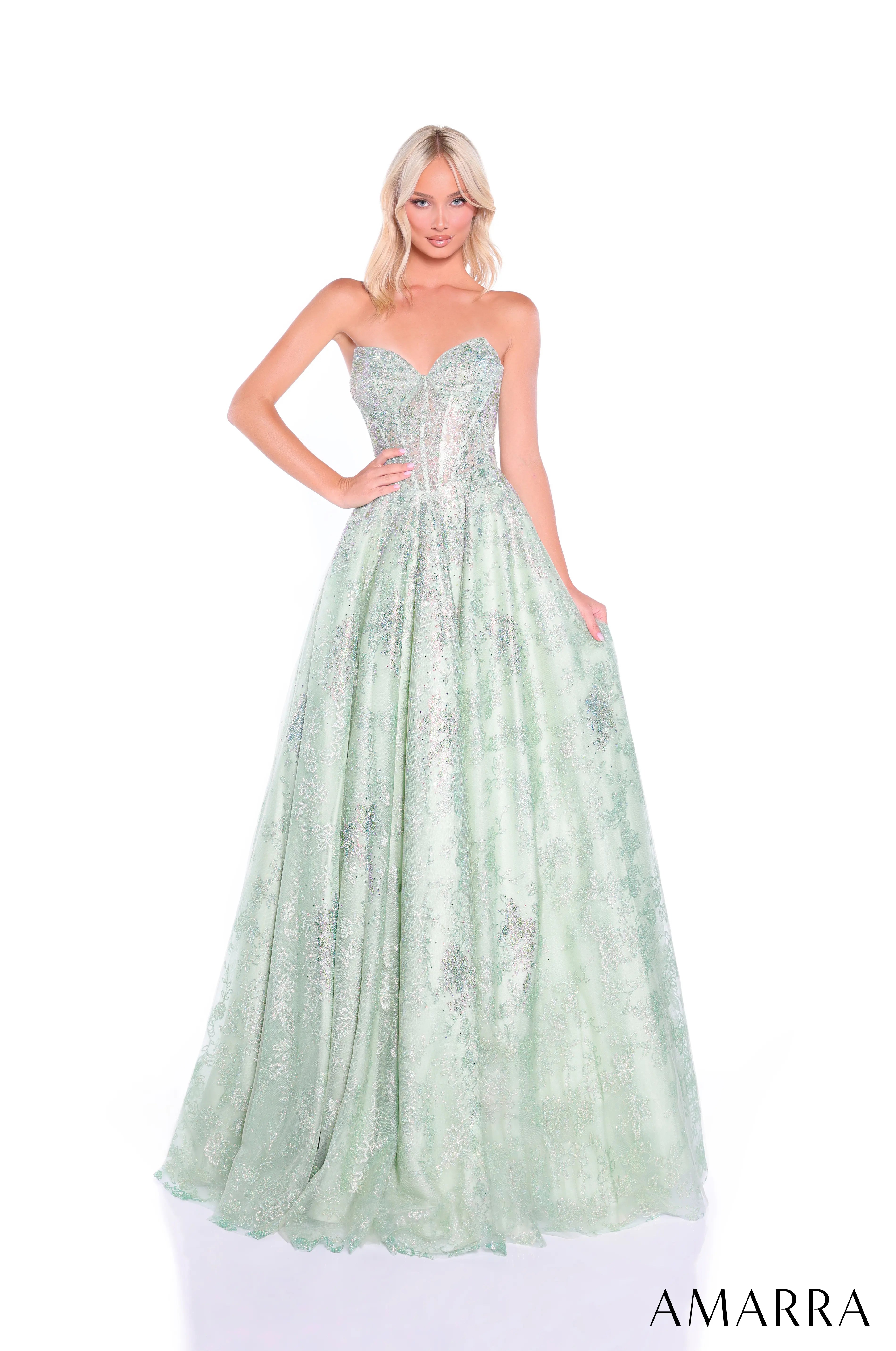 Woman wearing a light green evening gown with floral details on a white background, brand 'AMARRA' visible.