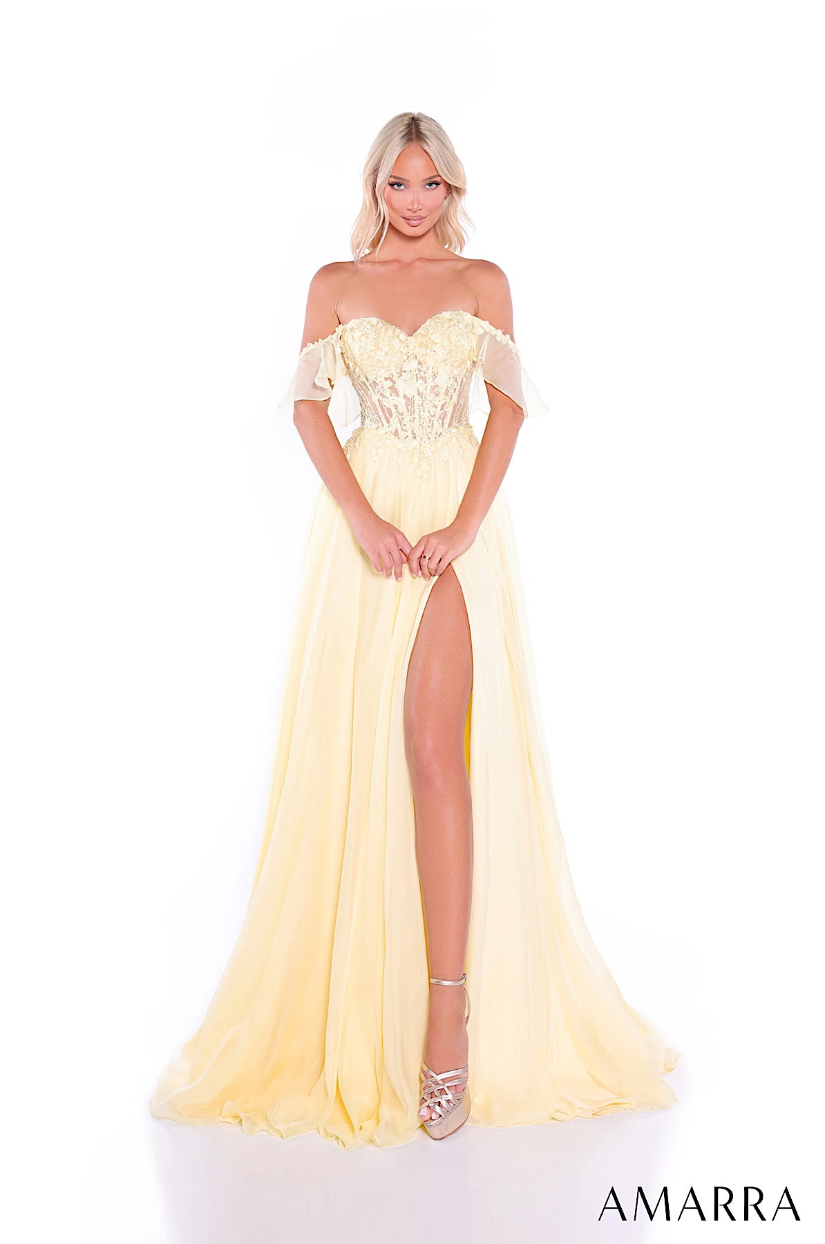 Woman wearing a light yellow off-shoulder evening gown with a high slit on a white background, featuring the brand 'Amarra'.