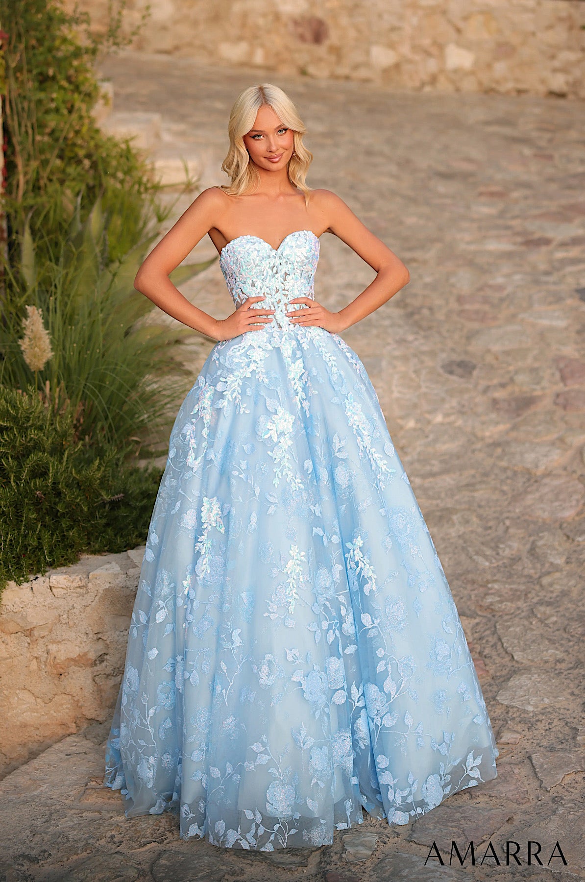 Woman wearing a light blue strapless gown with floral details outdoors.