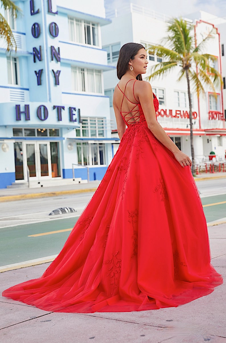 Woman in a red dress standing in front of a colorful hotel building.