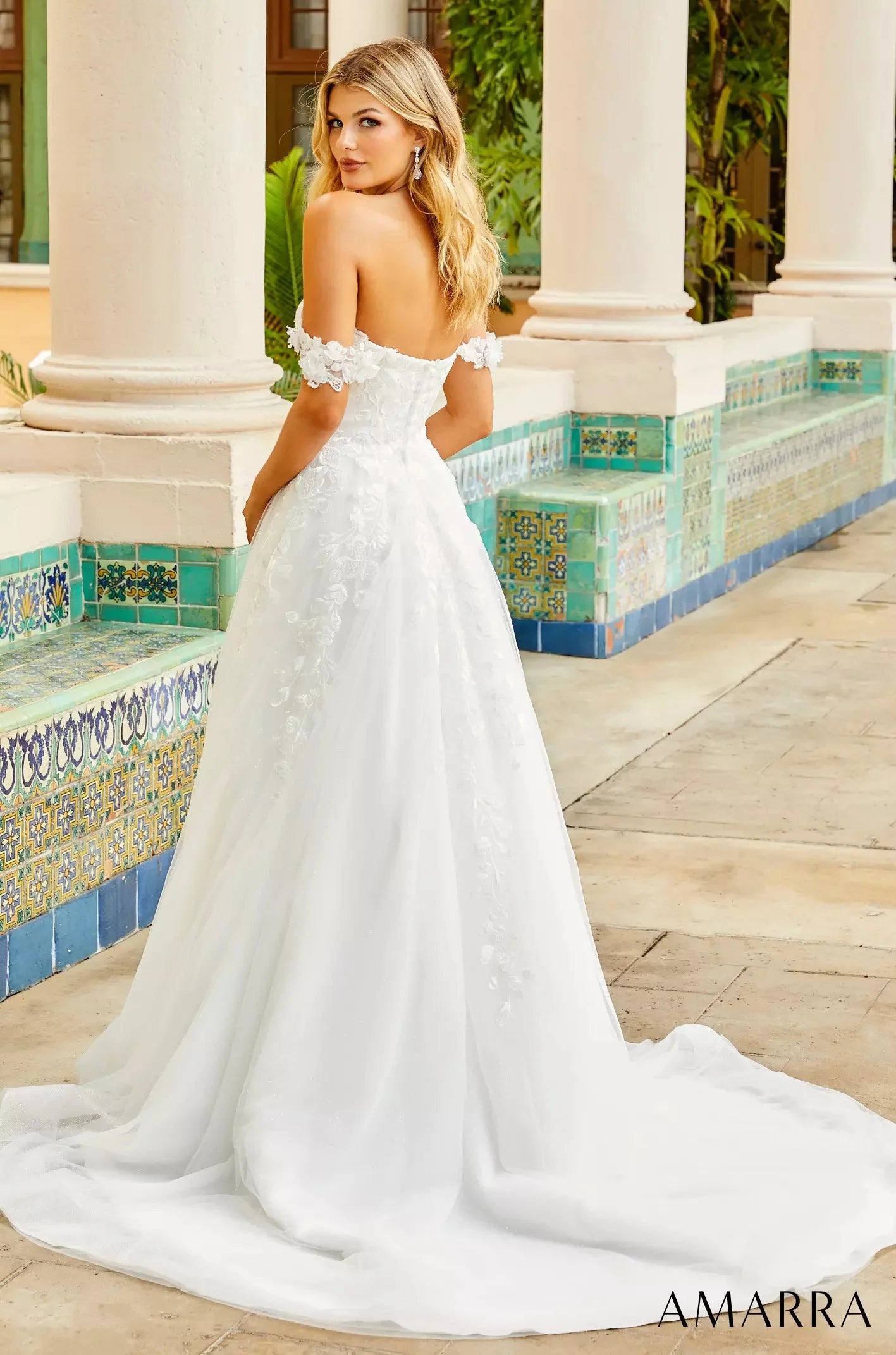 Woman in a white wedding dress standing in an outdoor setting with columns and a pool. with THE BRIDAL COMPANY branding.