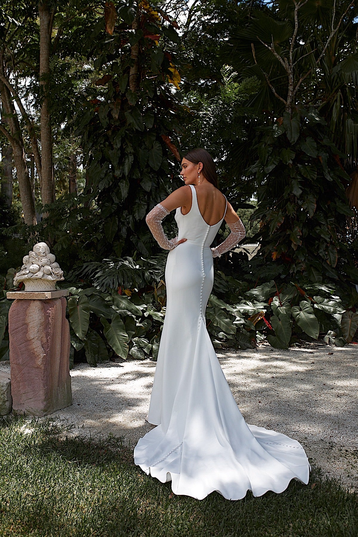 Woman in a white wedding dress standing in a garden setting