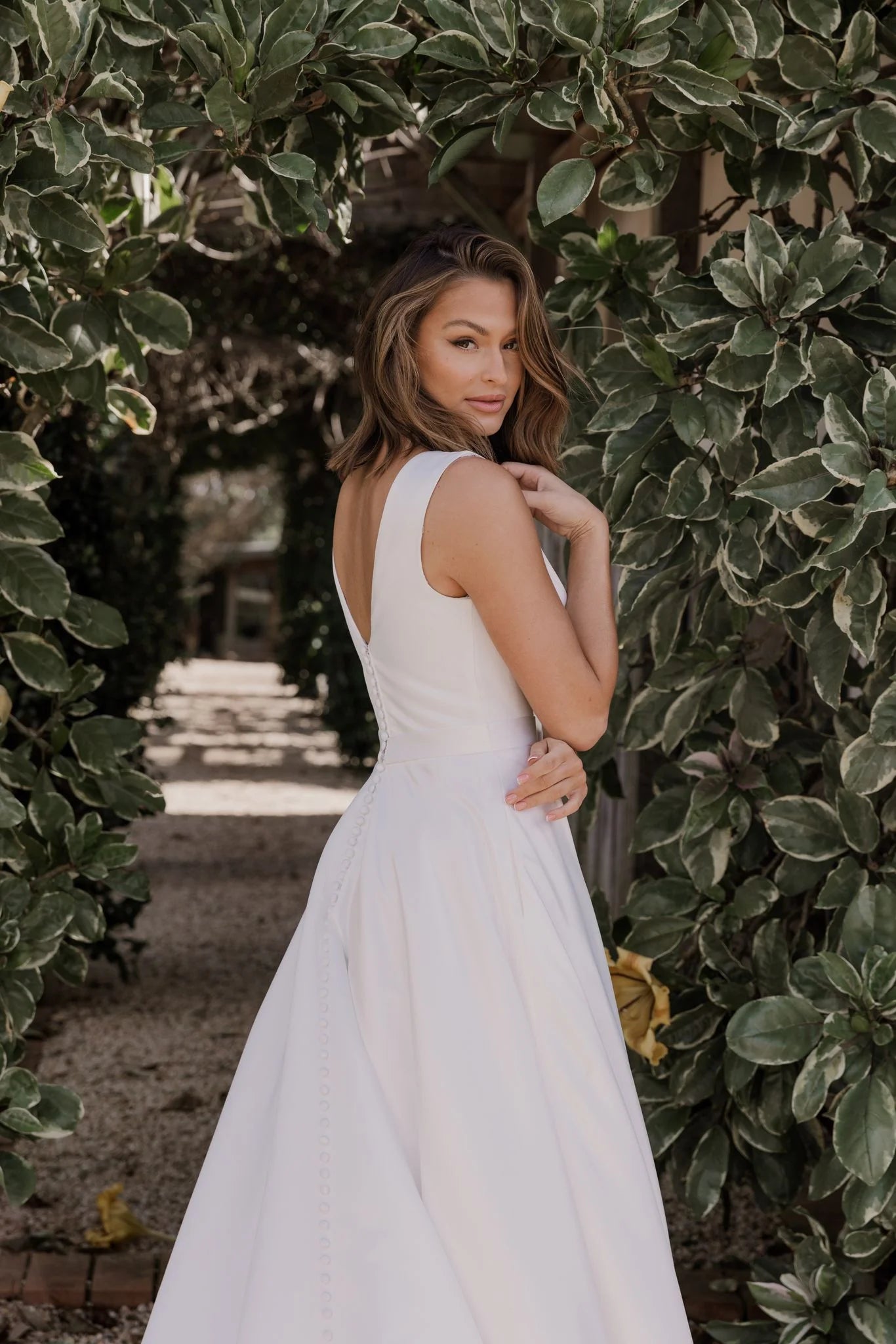 Woman in a white dress standing among green foliage