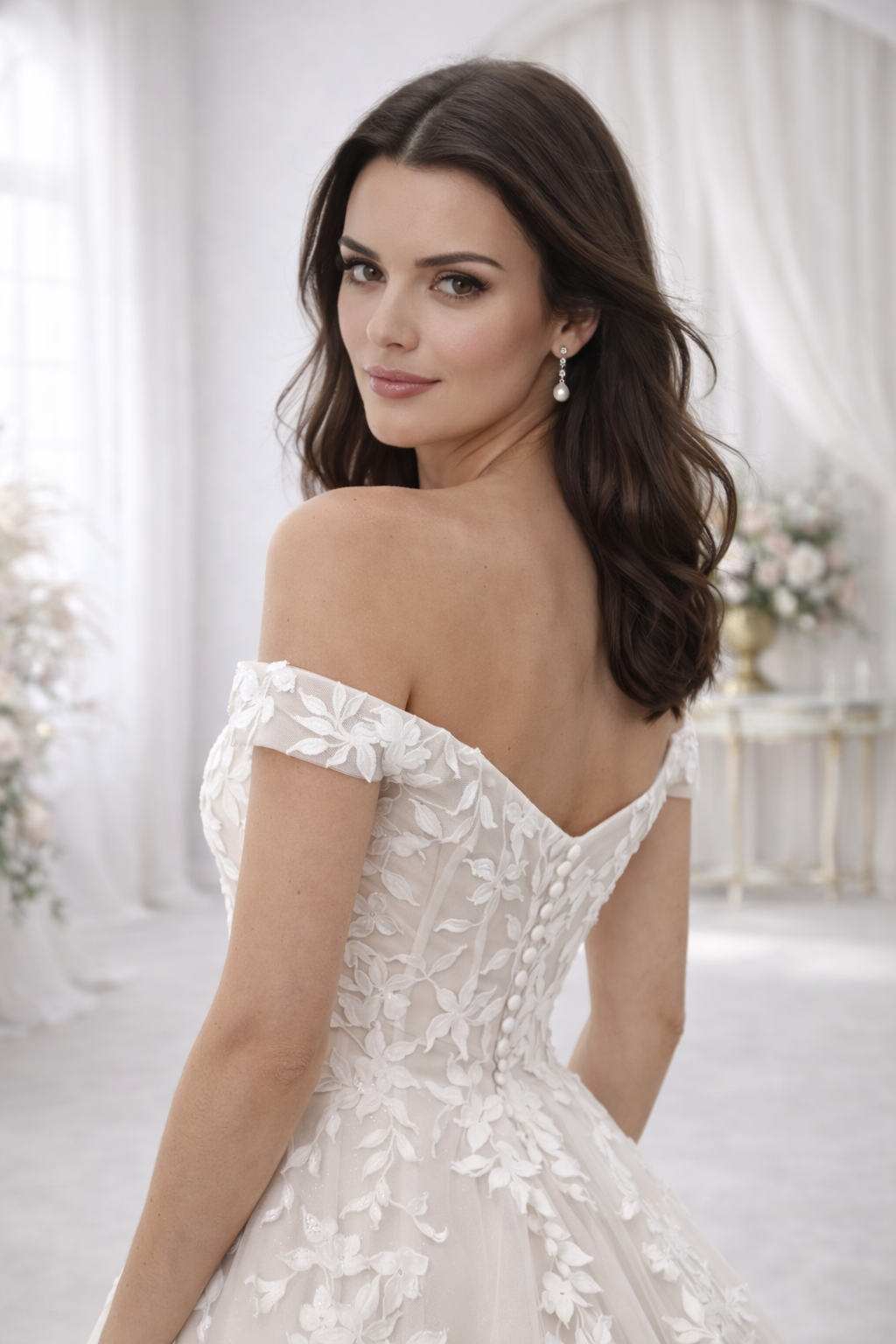 Woman wearing a white wedding dress with floral details in a softly blurred indoor setting